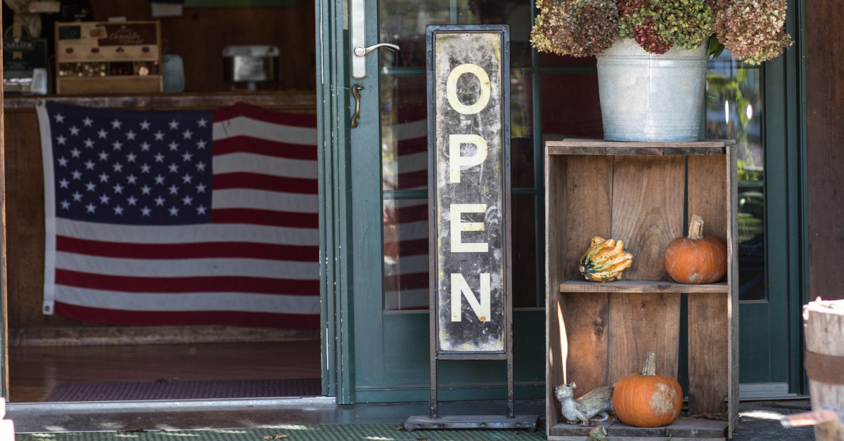 Open sign outside shop with US flag